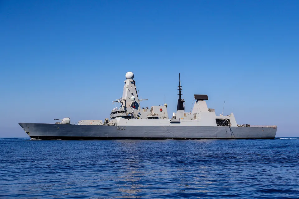 A large gray destroyer warship on blue water under a clear blue sky.