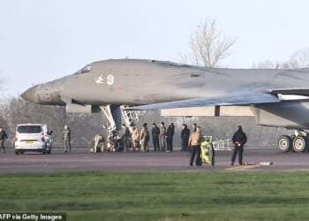 Personnel stand around a US Air Force B-1 Lancer bomber parked on the tarmac after it landed at RAF Fairford this morning after completing attacks on Iran