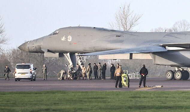 Personnel stand around a US Air Force B-1 Lancer bomber parked on the tarmac after it landed at RAF Fairford this morning after completing attacks on Iran