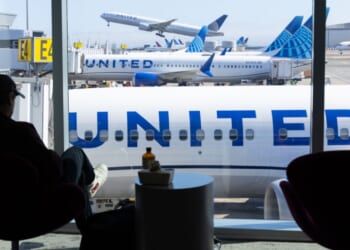 A man sits in an airport overlooking a United Airlines plane at San Francisco International Airport on Aug. 31, 2025.