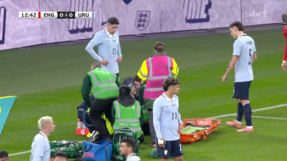 Medical staff tending to an injured player on a soccer field during a match between England and Uruguay.