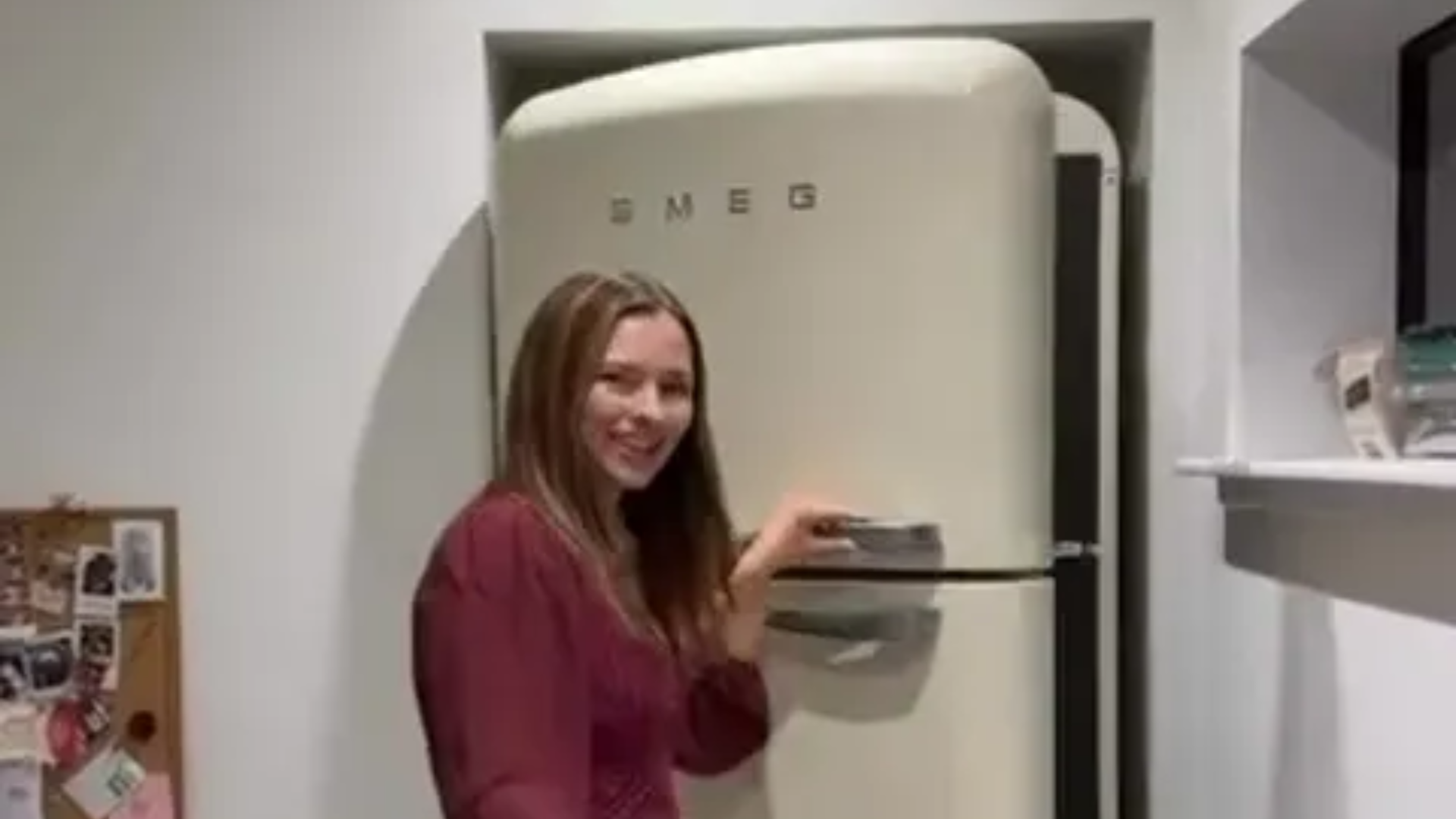 A woman opening a cream-colored SMEG refrigerator.