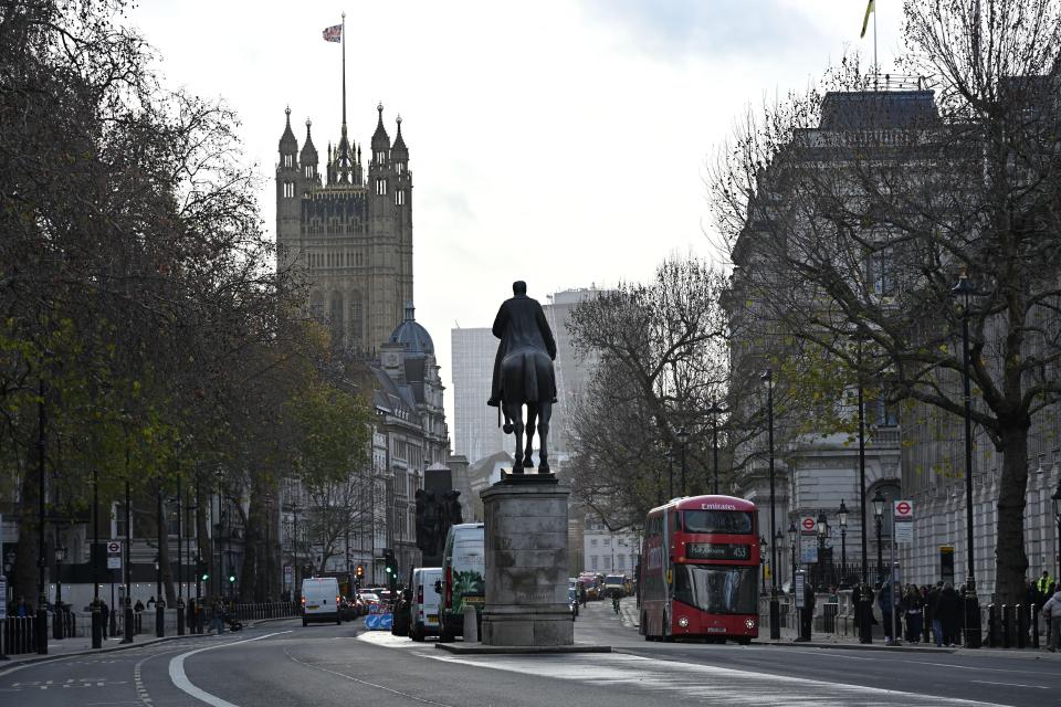 View looking down Whitehall towards The Houses of Parliament in central London, with a red double-decker bus.