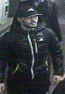 A man wearing a black baseball cap and a dark puffer jacket.