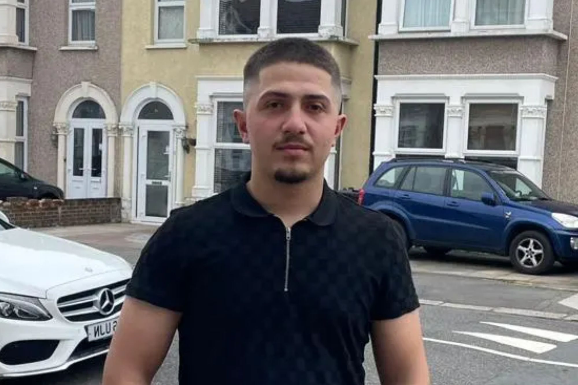 An image collage containing 1 images, Image 1 shows Renols Lleshi, a 19-year-old labourer, stands on a paved sidewalk with residential houses and parked cars in the background