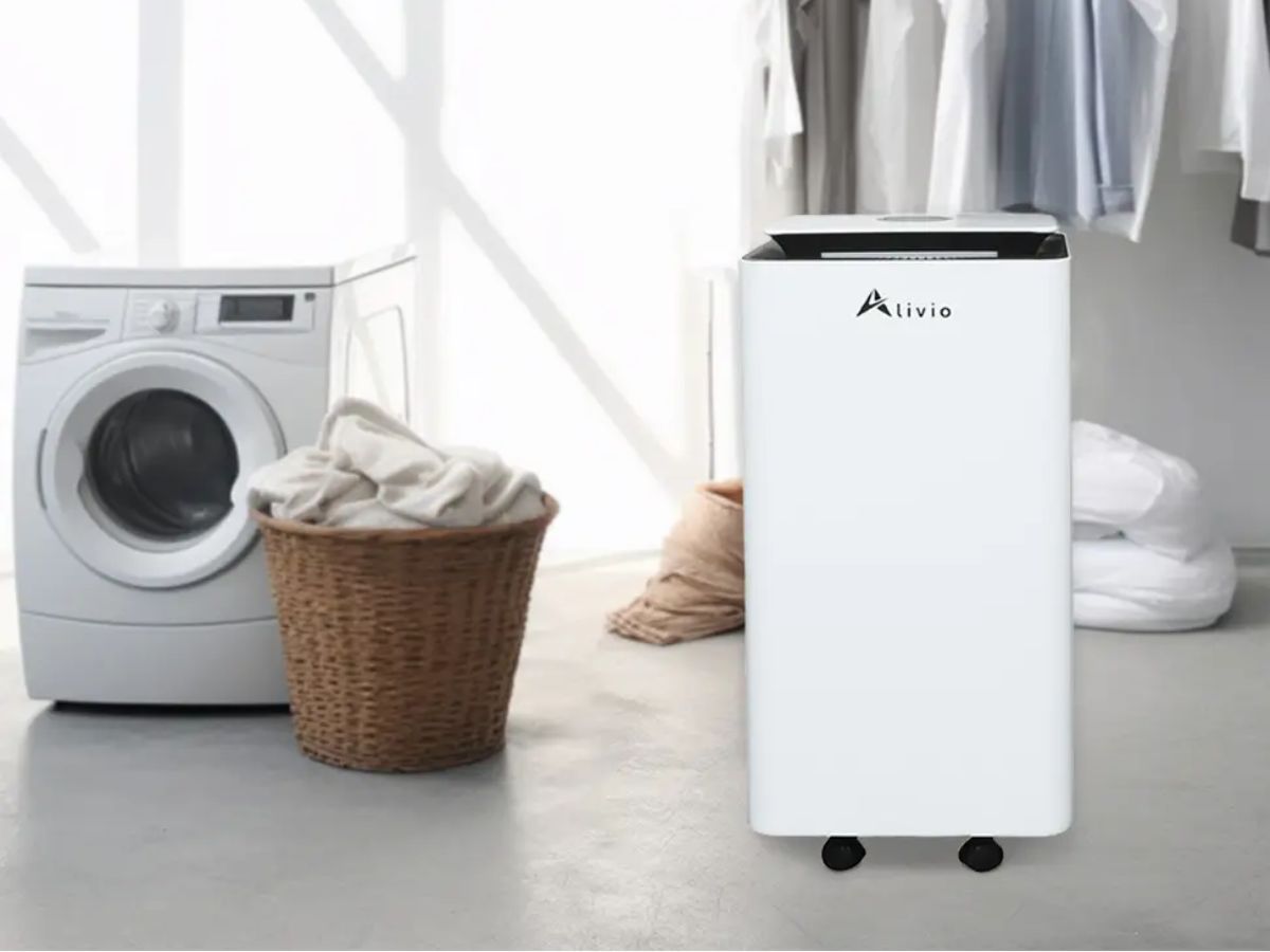 A white Alivio scrubber next to a washing machine, laundry basket, and drying clothes.