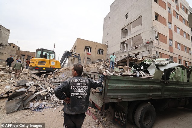 A digger removes the debris following damage to a residential building, in the Iranian capital