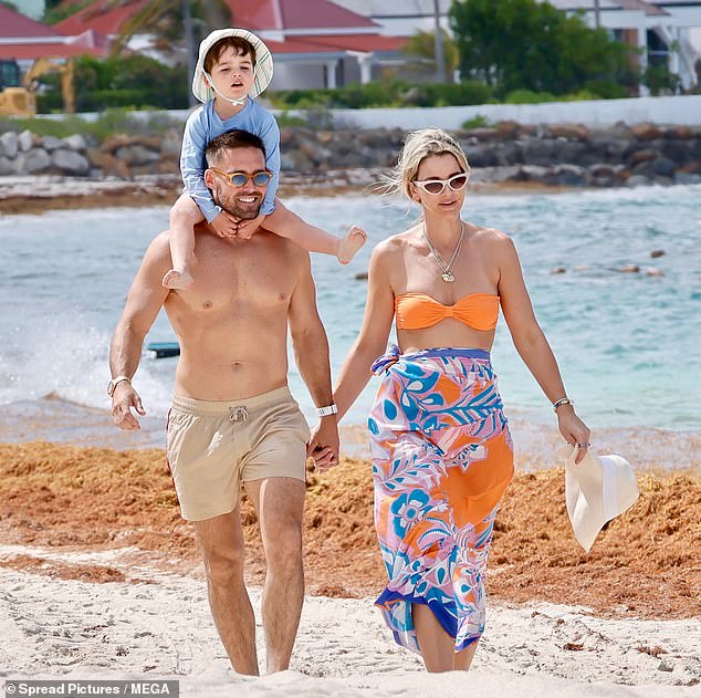 Little Otto held on tight as he balanced on his father's broad shoulders during a stroll along the shoreline on Tuesday