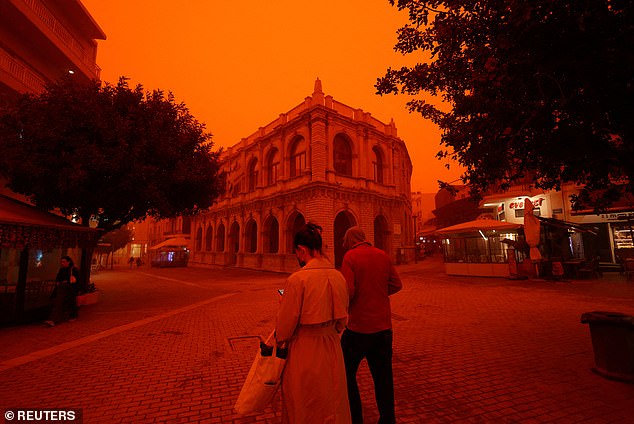 The violent weather has uprooted trees, damaged greenhouses and caused part of a wall at a ceramics factory to collapse (Two residents are pictured strolling through the centre of Heraklion on Wednesday)