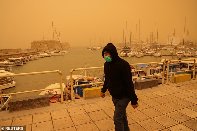 A man protects himself with a face mask, while walking in a haze caused by sand dust from the Sahara, due to strong southern winds, in Heraklion, Crete island, Greece April 1