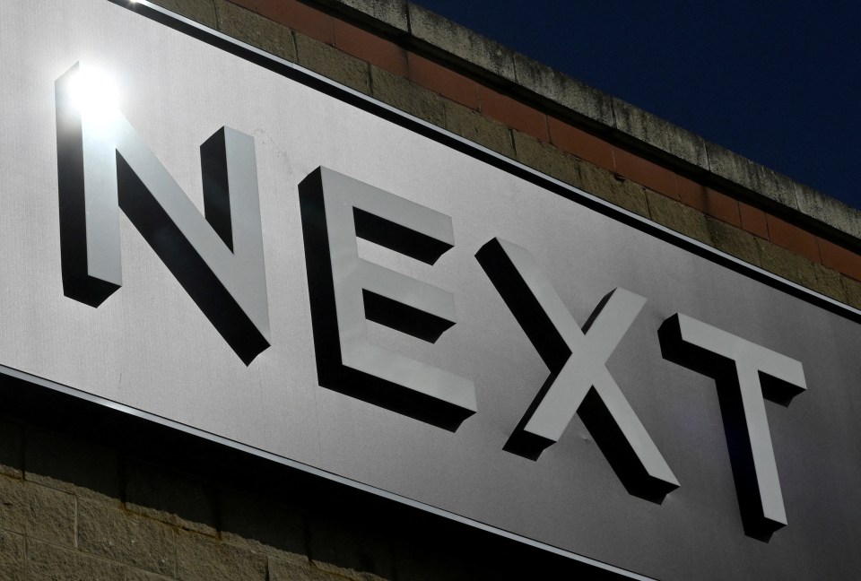 A close-up of the Next clothing store sign, with sunlight reflecting off the "N" in London.