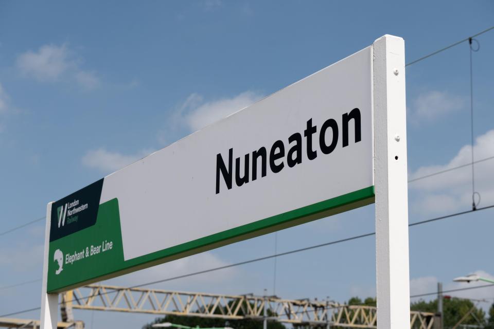 A sign at Nuneaton railway station in Warwickshire, UK, with the words "Nuneaton", "London Northwestern Railway", and "Elephant & Bear Line" against a partly cloudy sky.