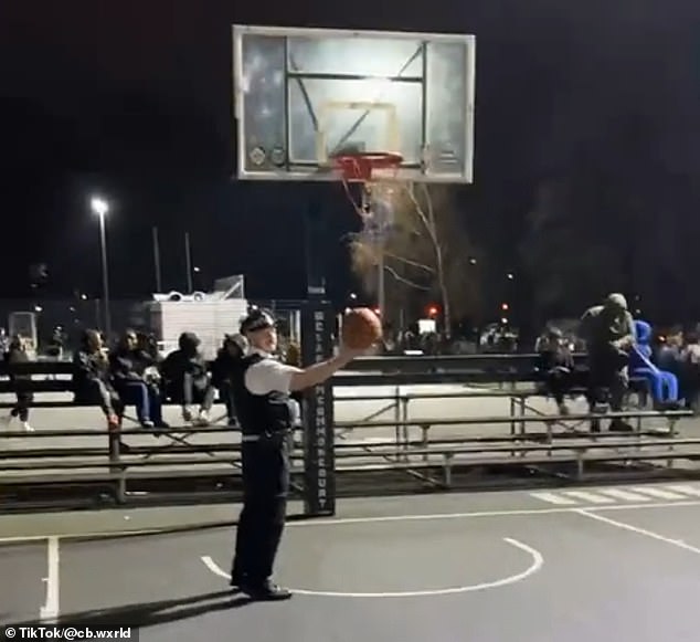 Police officer Kyp Kyriacou holds the ball at Clapham Common basketball courts on Tuesday. There is no suggestion any of the men in the video were involved in any criminal wrongdoing