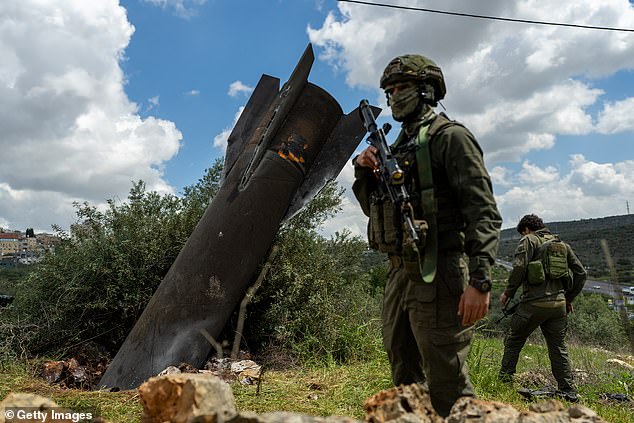 Israeli soldiers stand near an Iranian missile embedded in the ground last week