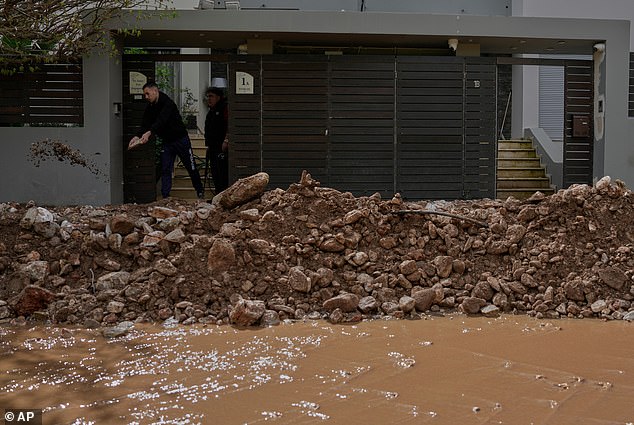 A man shovels mud from his house in Nea Makri, east of Athens, Thursday, April 2, 2026, after heavy overnight storms caused extensive damage