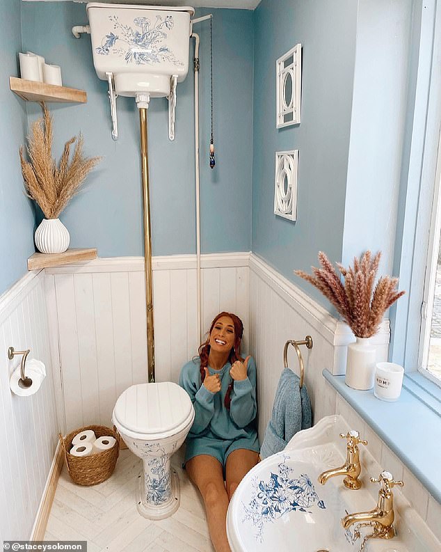 Stacey posing in one of the bathrooms, with the walls painted pastel blue