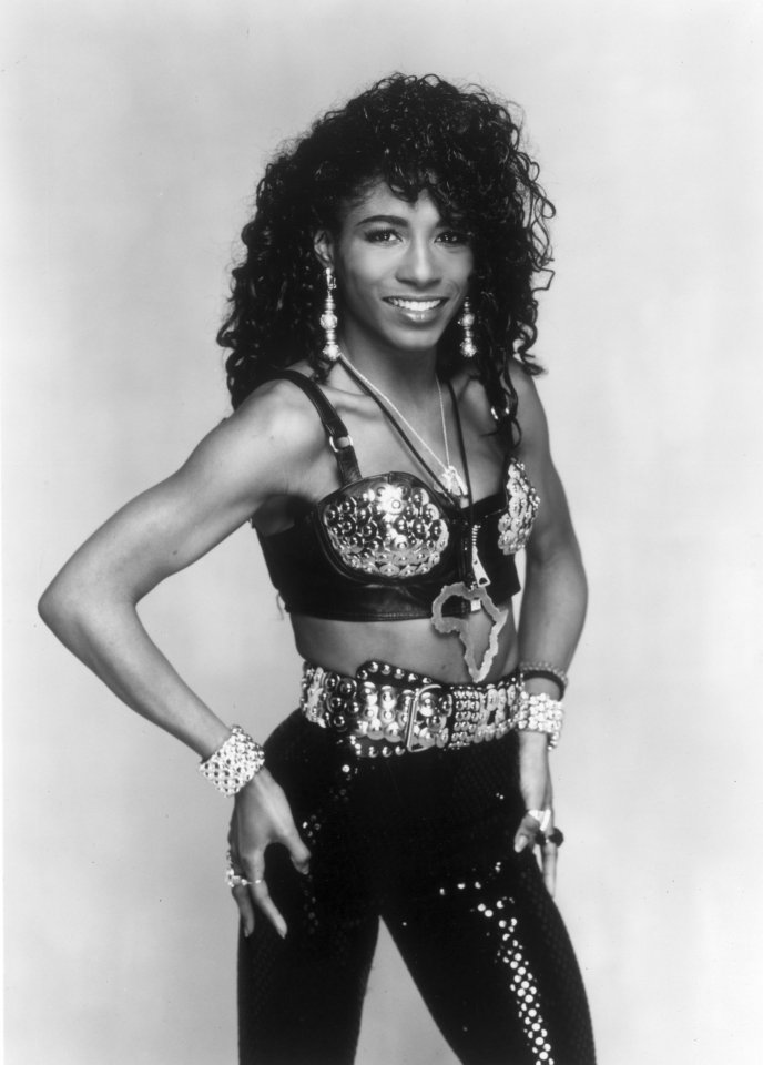 Sinitta, a pop star, wearing a studded bra, belt, and sequined pants.
