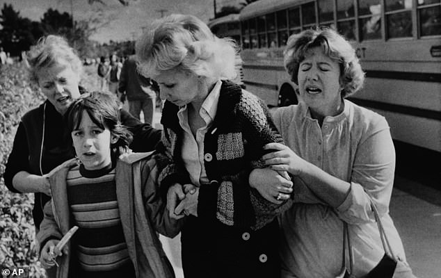 Pictured: A schoolboy who was evacuated by bus to a nearby high school after the shooting is greeted by unidentified women