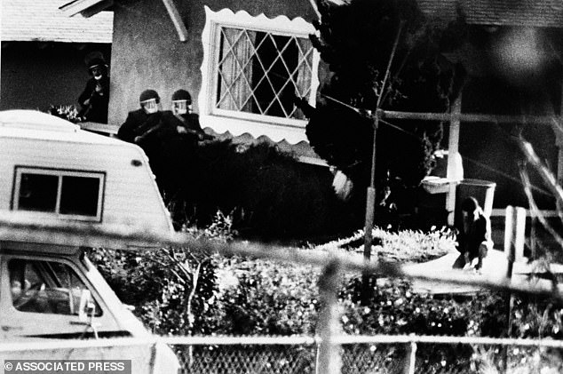 Police quickly descended on the scene - and one officer soon noticed movement at the front door of the house directly across the street from the school. Pictured: SWAT teams enter the property