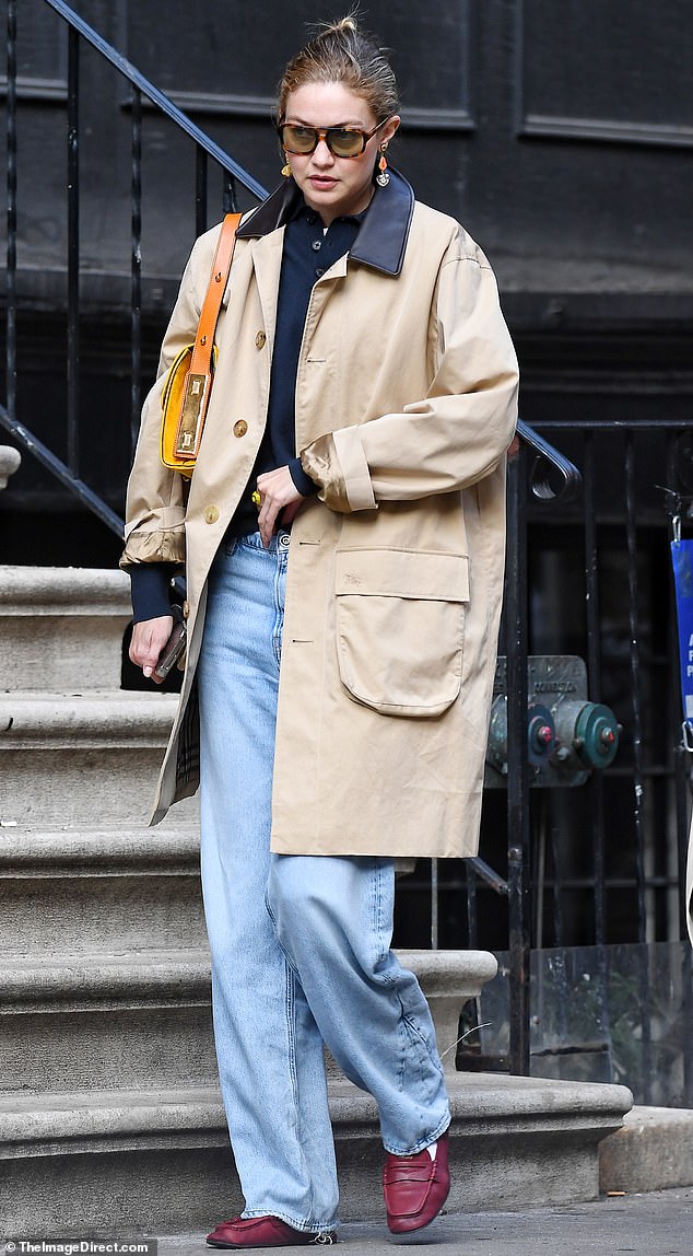 She was stylishly casual in a dark navy shirt as well as a pair of light blue jeans and a tan coat layered on top