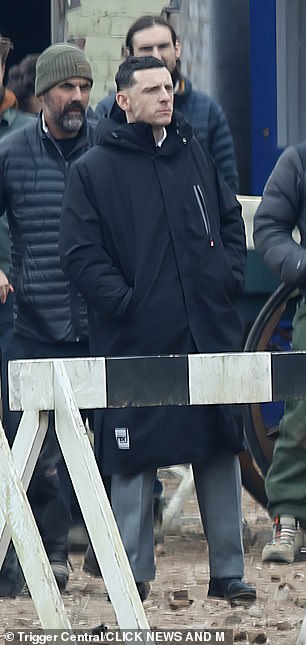 During a break in filming he wrapped in a padded black coat