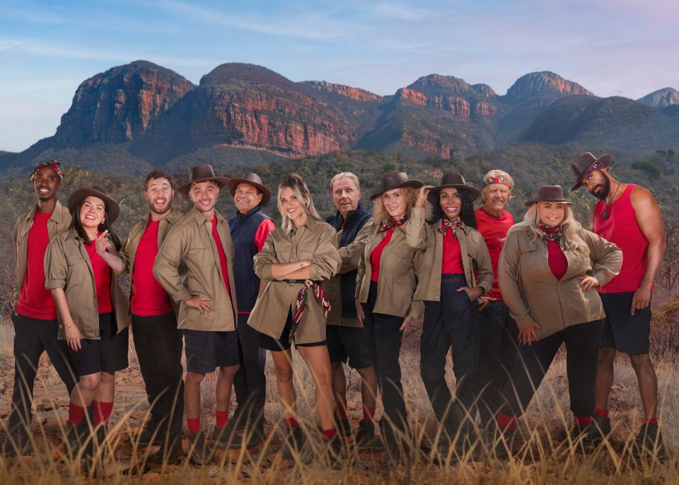 Cast of "I'm a Celebrity... Get Me Out of Here! South Africa" posing in safari outfits in front of mountains.