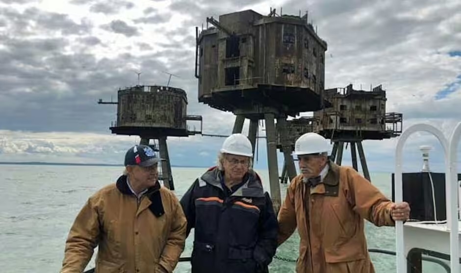 Three men standing in front of sea forts, one identified as "Mad" Mike Smith on the right.