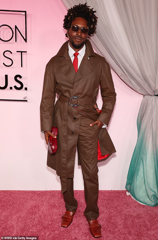 SAINt JHN demonstrated his winning sense of style in a brown suit with a raincoat-style jacket that featured crimson lining to match his tie