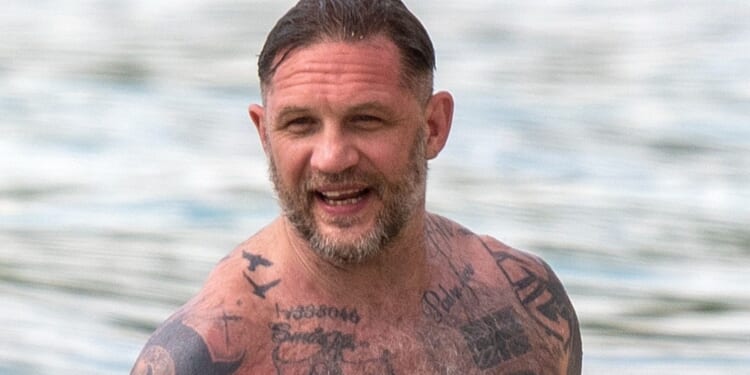 Tom Hardy shows off HUGE tattoo collection as topless star hits the beach with wife Charlotte Riley