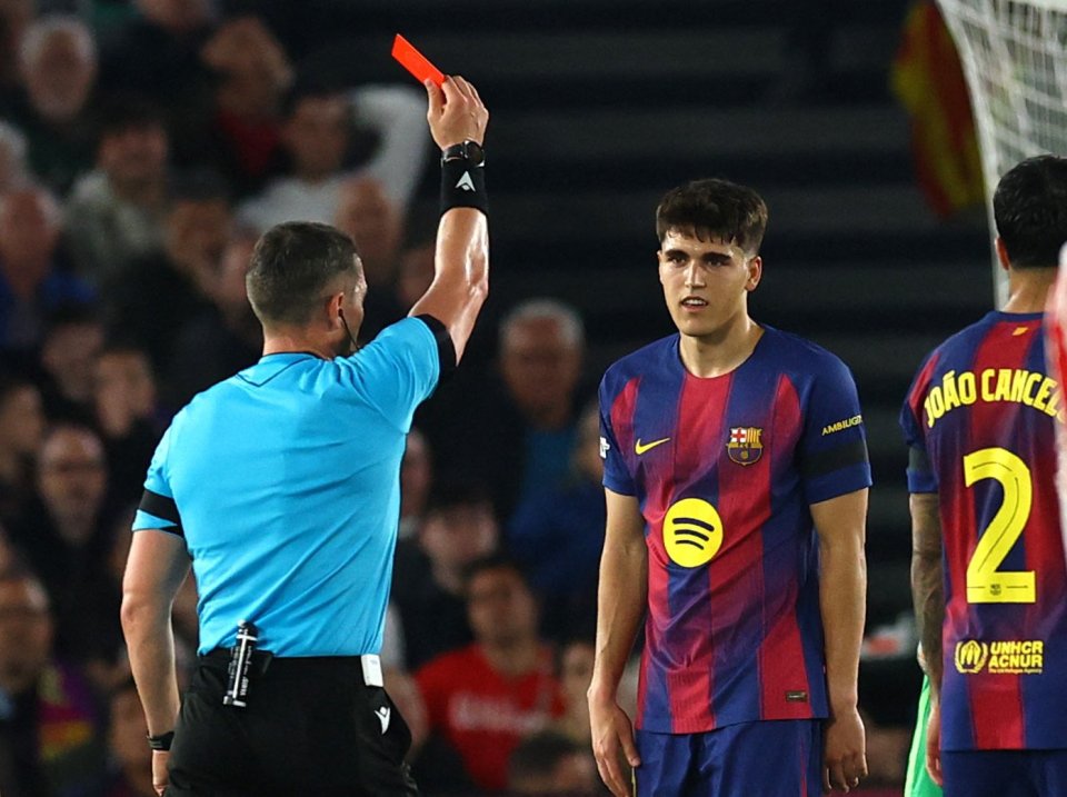 Referee issuing a red card to a Barcelona player during a UEFA Champions League quarter-final match against Atletico Madrid.