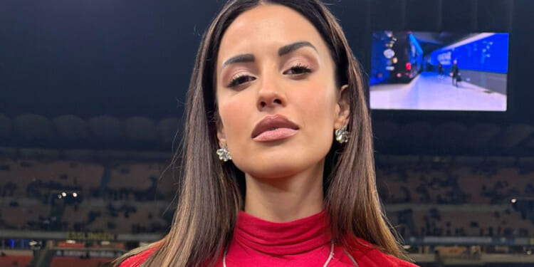 Glamorous TV host and football Wag causes a stir on the sidelines in low-cut top as fans driven wild