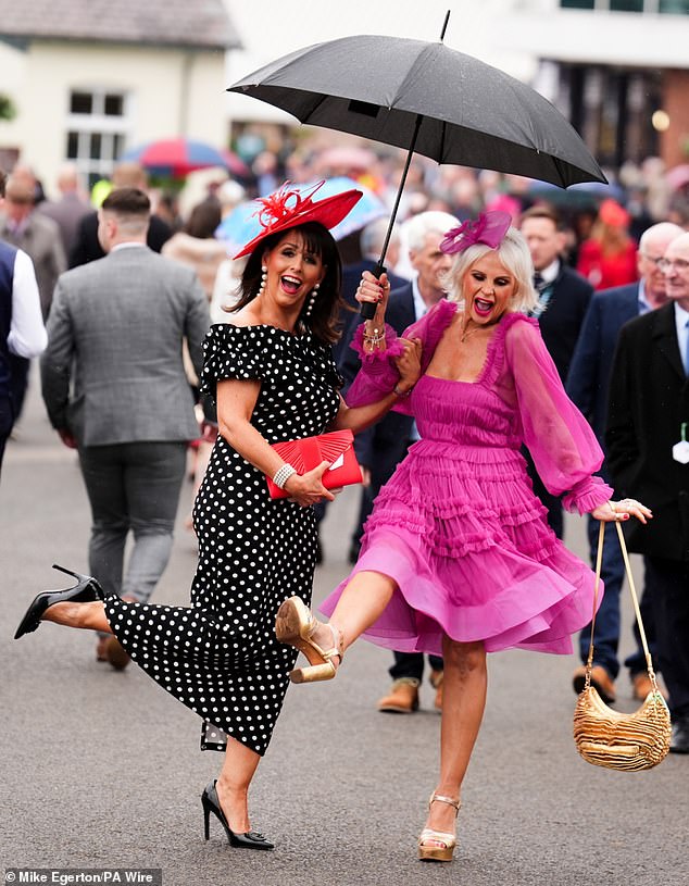 Having a brolly good time! Beaming racegoers show off their moves as they dance in the rain