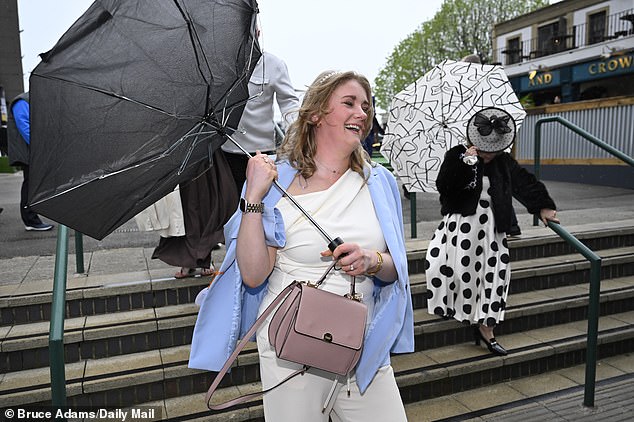 Racegoers lose control of their umbrellas as they arrive at the three-day festival