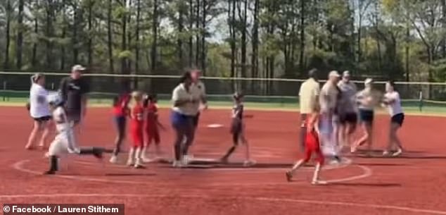 The coach is seen yanking the other woman by her shirt and pulling her hair as they both tumble back into the dirt