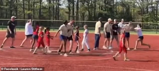 Other parents are heard shouting at the girls to 'get in the dugout' amid the screaming and chaos