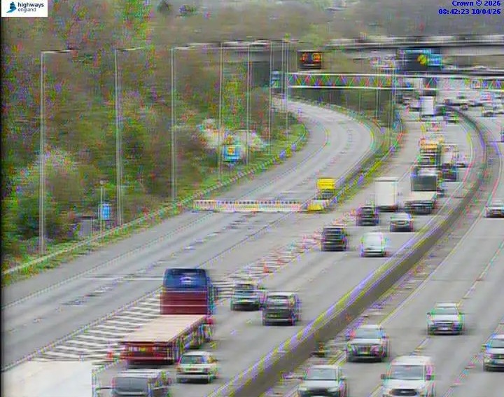 Traffic camera view of a multi-lane highway with moving vehicles.