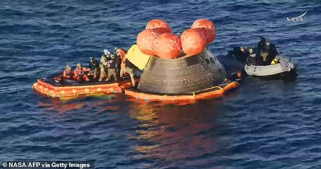 Artemis II crewmembers (in orange suits) being extracted from their spacecraft after splashing down in the Pacific Ocean off the coast of San Diego, California