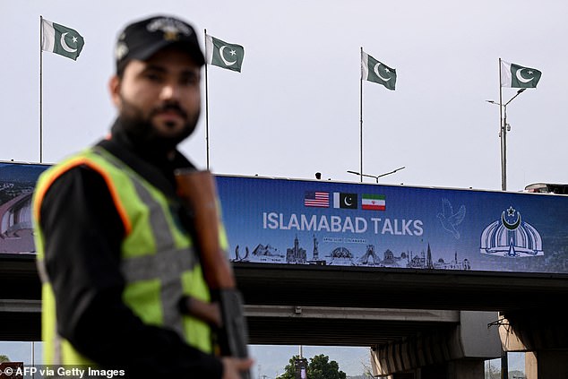 A policeman stands guard in front of a digital screen displaying news of US-Iran peace talks