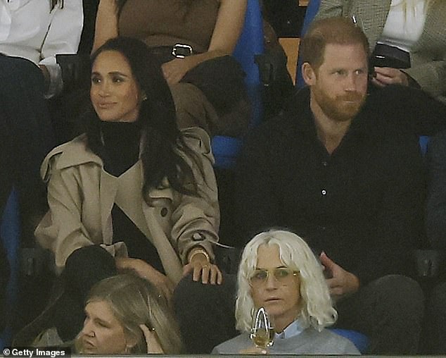 The Duchess of Sussex rests her hand on Harry's knee at the Super Rugby match between the NSW Waratahs and Moana Pasifika at Sydney's Allianz Stadium
