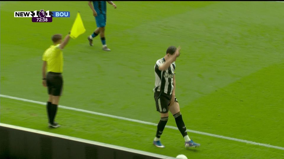 An assistant referee holding up a yellow flag while a Newcastle player walks by, with the score NEW 1-1 BOU and 72:38 on the clock.