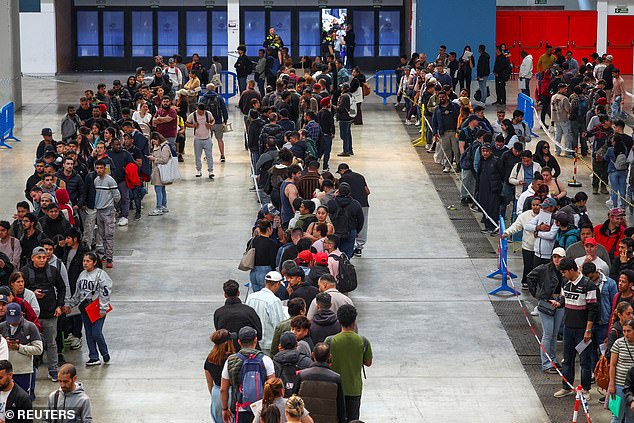 People queue to receive documentation as Spain's mass migrants regularisation process started on Monday