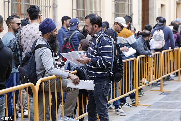 An official assists migrants waiting for their documents to be processed at Valencia City Hall in Valencia, Spain
