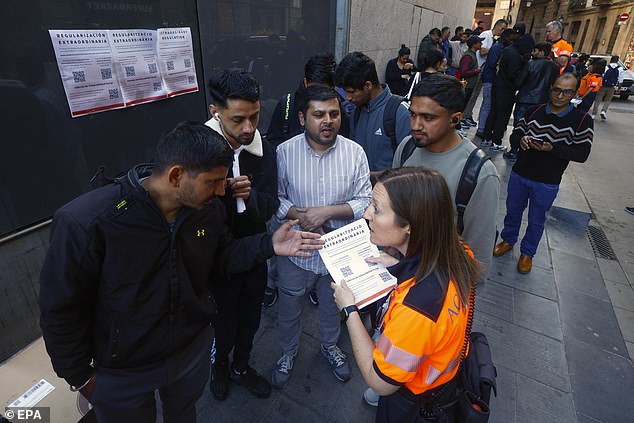 An official assists migrants waiting for their documents to be processed at a citizen service office in Barcelona, Spain