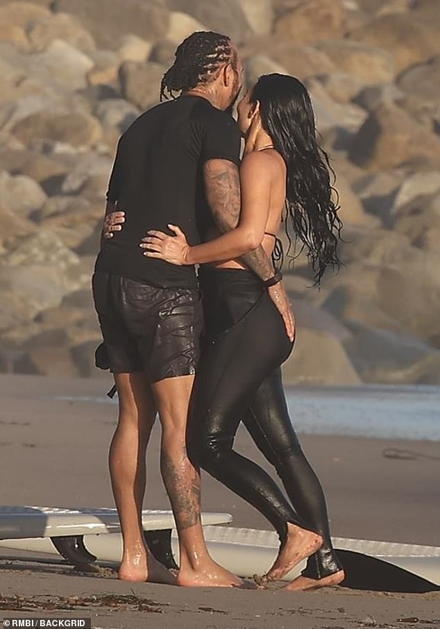 The lovebirds could not keep their hands off each other as they stood barefoot on the shore
