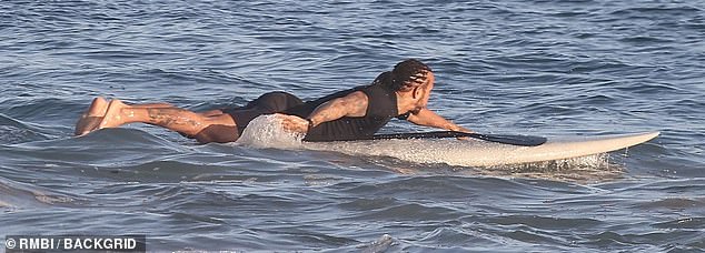 The F1 driver was also seen paddling his board out