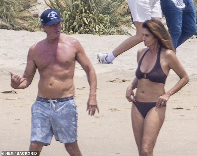 She was makeup-free while strolling the sand in her two-piece swimsuit, which bared her cleavage and taut tummy