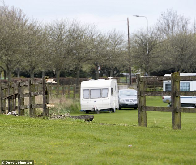 Pictured: A hole in the fence at the site. More than a dozen caravans are parked up on the plot of land - which sits at a junction of the M8 and M9 motorways near Edinburgh Airport