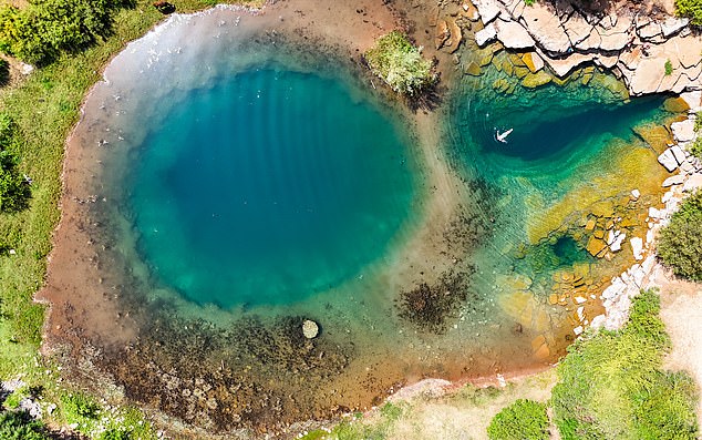 Syri i Gjonit spring receives meltwater and rain from nearby limestone hills, creating vivid turquoise and lush green water