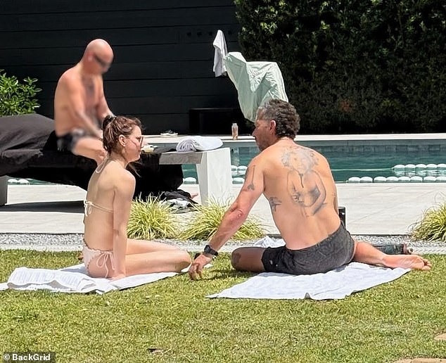 At Spyre, photos show the actor shirtless, relaxing outside on a towel, with what appears to be his new girlfriend Nicole Mumphrey