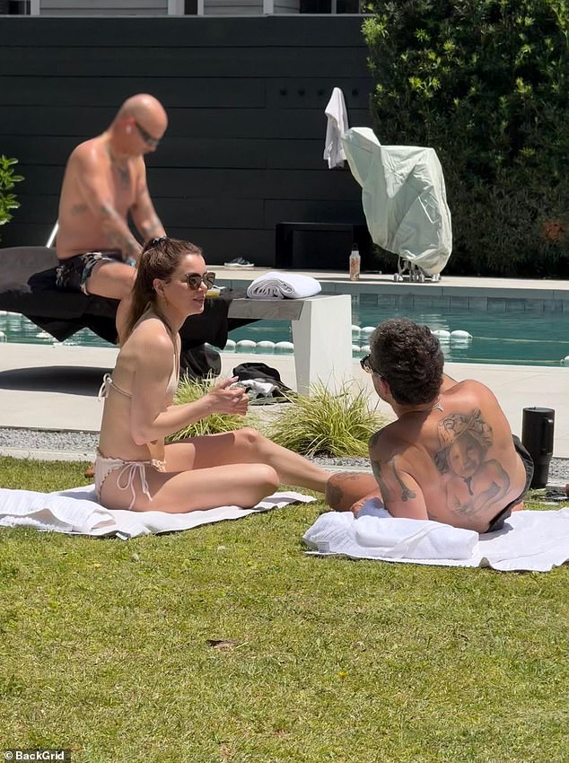 The snaps from Thursday show him kissing her thigh as she lounged in a bikini, reportedly drawing the attention - and exasperation - of fellow patrons